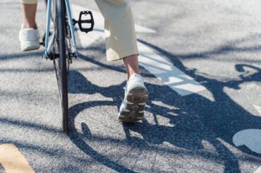 Person riding bicycle on a sunny street.